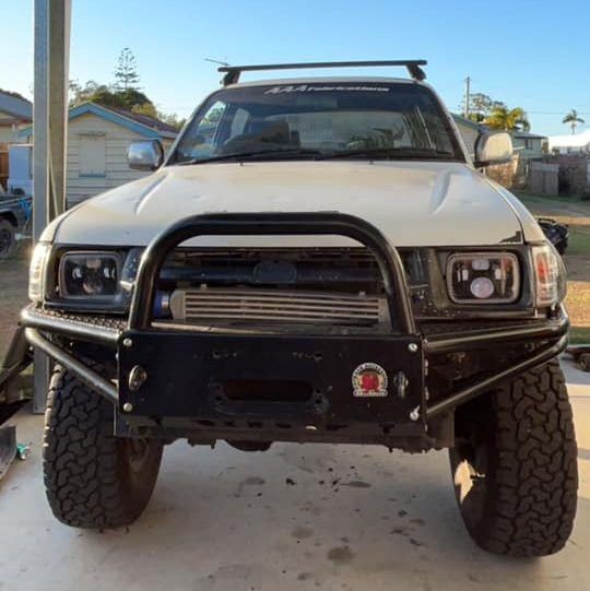 Front view of a rugged 4WD vehicle equipped with an off-road bumper, roof rack, and heavy-duty bull bar, parked outdoors. This 4WD setup from Explore Off Road showcases essential accessories for off-road adventures, highlighting durable and reliable modifications suitable for challenging terrains. Perfect for 4WD enthusiasts looking for high-quality off-road parts and accessories in Australia.